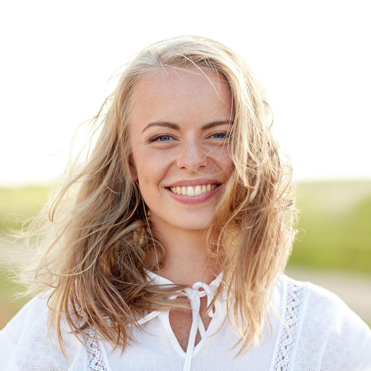 happiness, country, summer holidays, vacation and people concept - close up of happy smiling young woman or teenage girl with wild hair outdoors